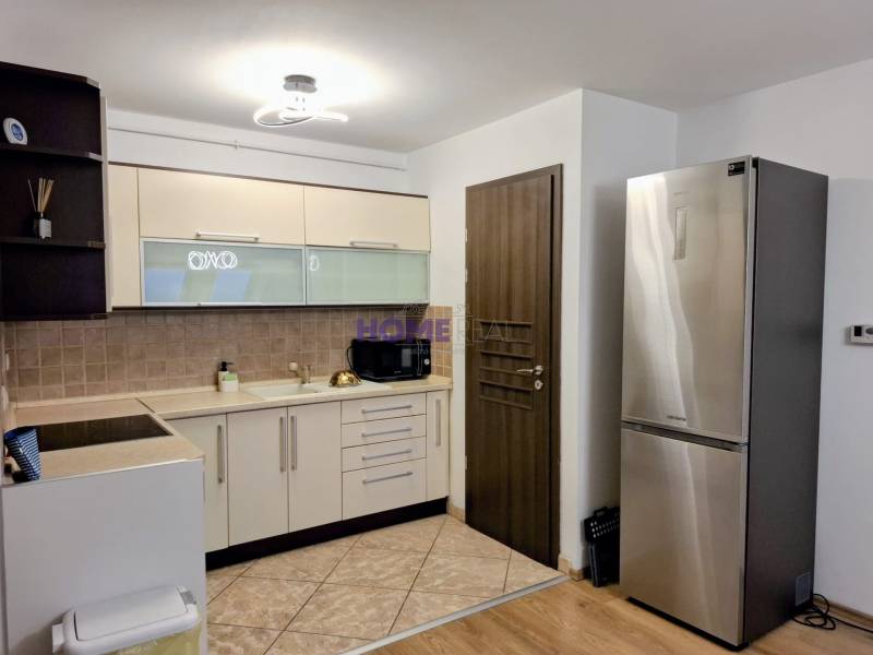 A kitchen in a 3-room apartment with white cabinets and a stainless steel refrigerator.