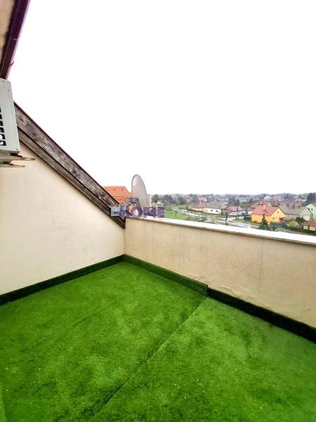A balcony with artificial grass in a 3-room apartment offers a view of the rooftops.