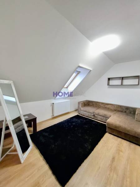 A room in a 3-room apartment with a wooden decor floor, a carpet, and a sofa bed.