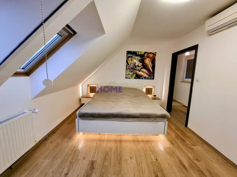 A bedroom in a three-room apartment with a wooden decor floor and art on the wall.