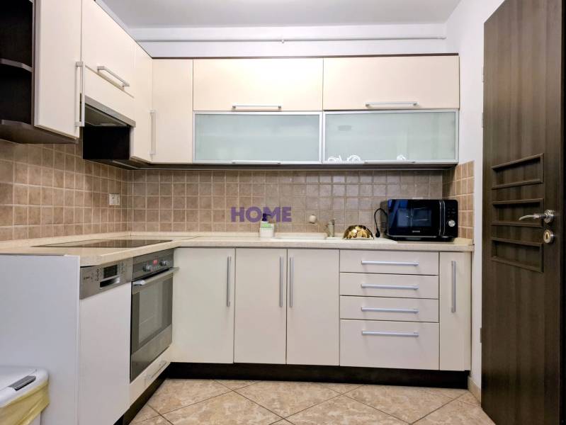 A kitchen in a 3-room apartment with tiles and appliances, cream-colored cabinet doors.