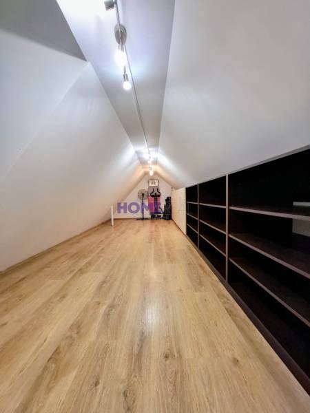 Attic room in a 3-room apartment with a wooden decor floor and shelves.