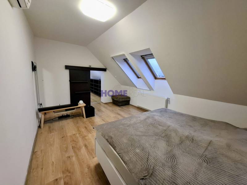 A bright bedroom with wood-patterned flooring in a three-room apartment.