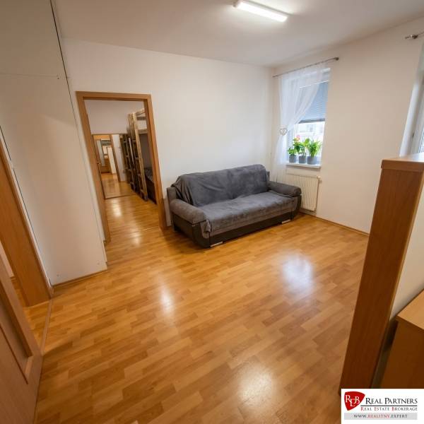 A room with a sofa bed, a window, and a floor with a wooden decor in a 2-room apartment.