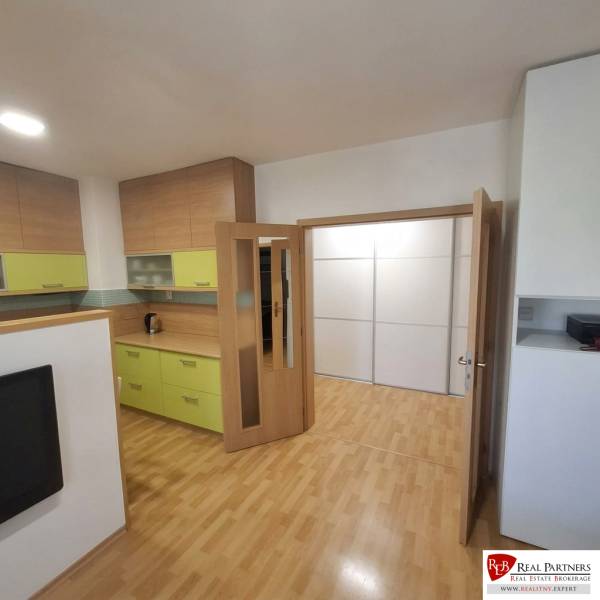 Kitchen and living room in a 2-room apartment with wood-patterned flooring.