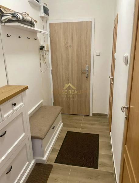 A hallway in a 3-room apartment with a coat rack, a bench, and an entrance door.