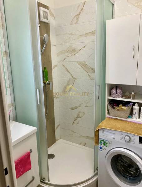 A bathroom with a shower and a washing machine in a 3-room apartment.