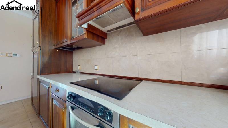 A kitchen in a 5 or more room apartment with wooden cabinets and ceramic tiles.