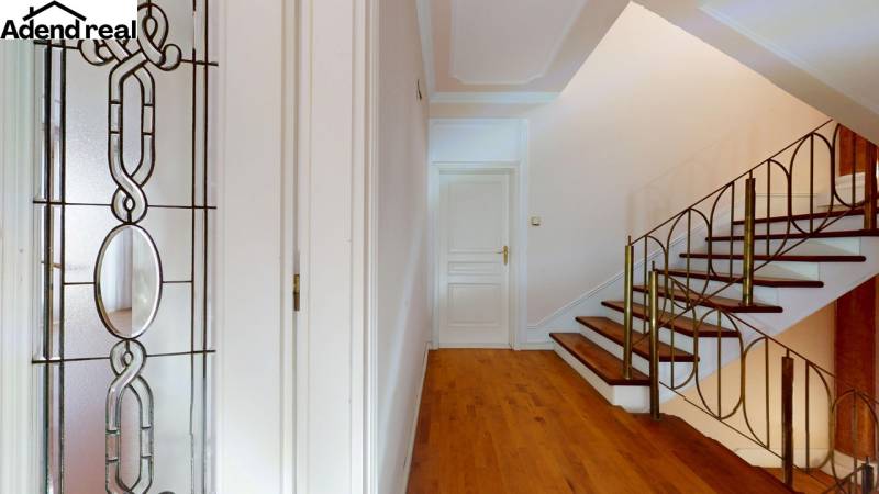 A hallway with a decorative glass panel, staircase, and flooring with a wood decor in a 5 or more room apartment.