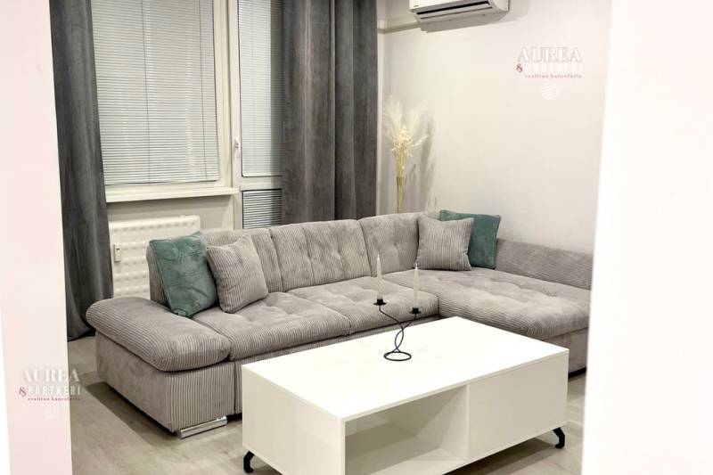 Living room in a two-room apartment with a gray sofa and a white table.
