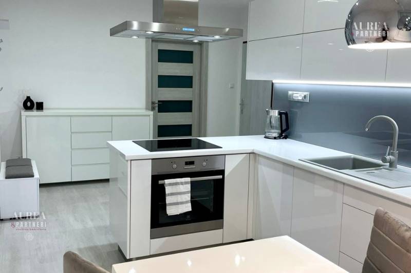 A kitchen in a 2-room apartment with white cabinets and built-in appliances.