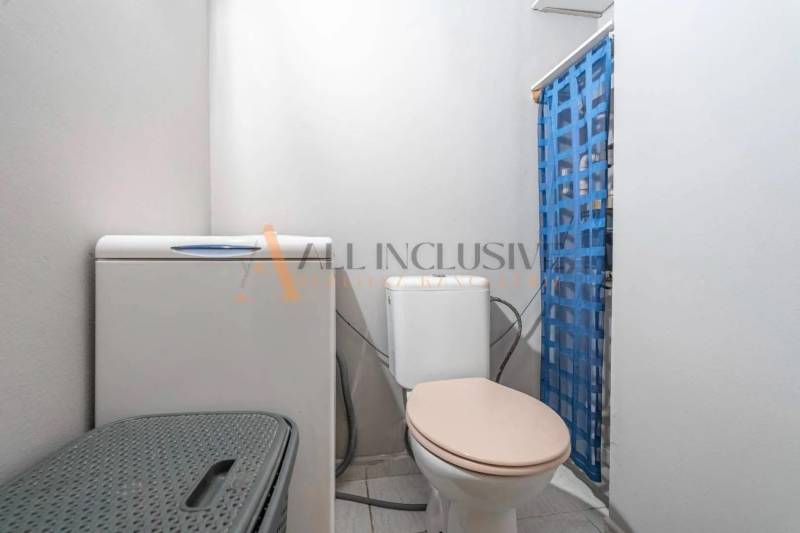 A bathroom in a 3-room apartment with a washing machine, toilet, and blue curtain.