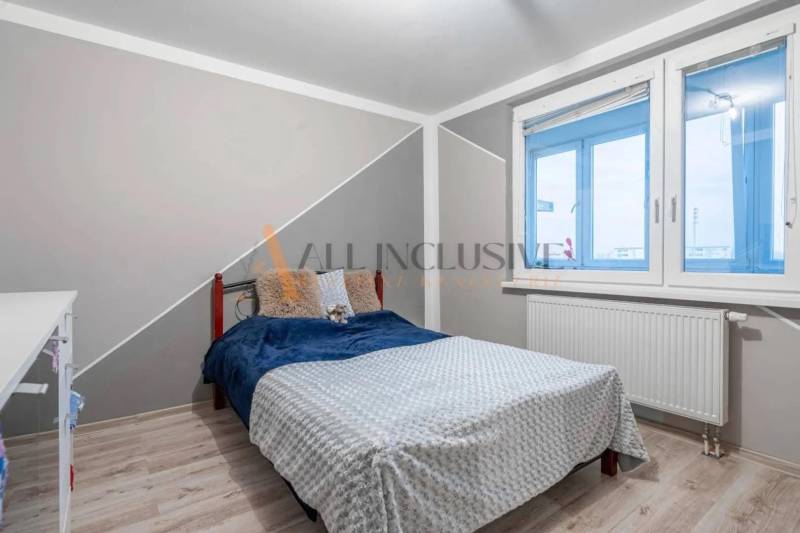 A bedroom with a bed, a table, and a wooden decor floor in a 3-room apartment.