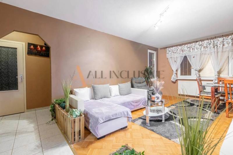 Living room in a three-room apartment with a wooden decor floor and a comfortable sofa.