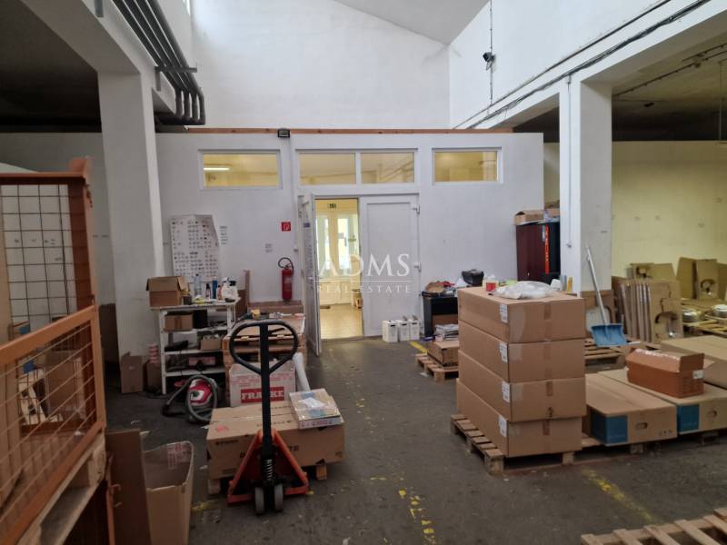 Warehouses and halls with stocked goods on pallets and a handling trolley.