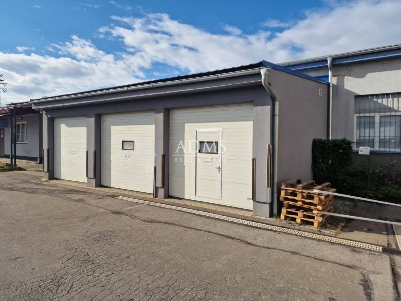 Warehouses and halls in Žilina with sectional garage doors and pallets next to the building.