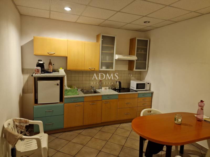 Kitchen corner with wooden cabinets, microwave, refrigerator, and table in warehouses and halls.