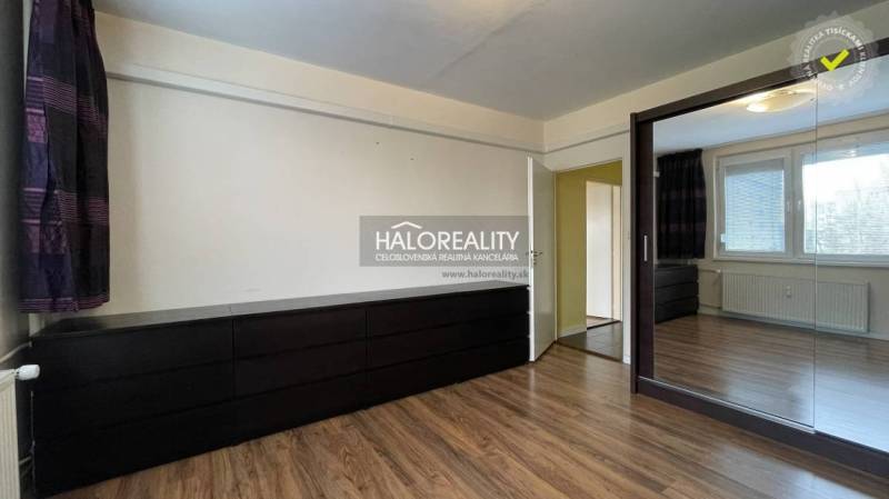 A room with a wooden decor floor, a mirrored wardrobe, and a chest of drawers in a 3-room apartment.