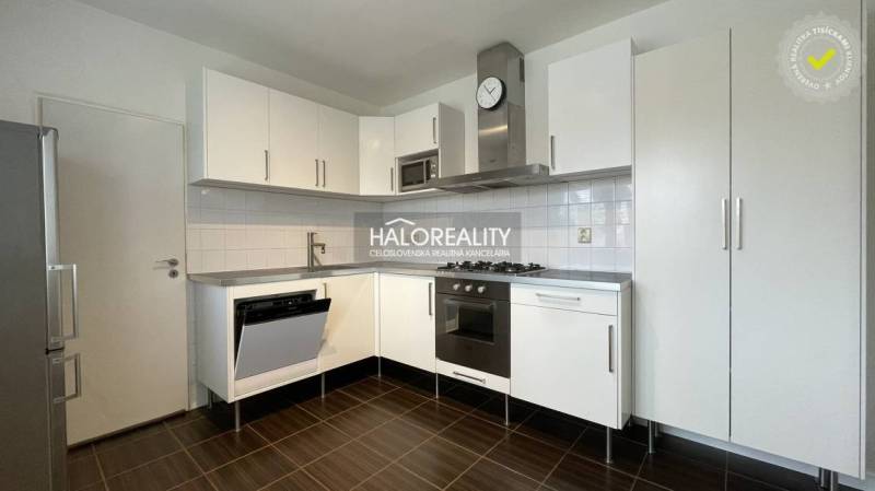 A kitchen with built-in appliances, white cabinets, and a dark floor in a 3-room apartment.