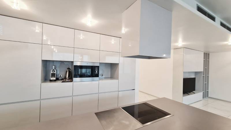 A kitchen in a 3-room apartment with white cabinets and built-in appliances.