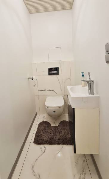 Toilet with a sink in a 3-room apartment; white tiles with a decor.