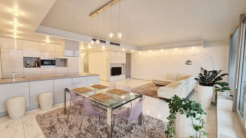 Living room in a three-room apartment with white furniture and a glass table.