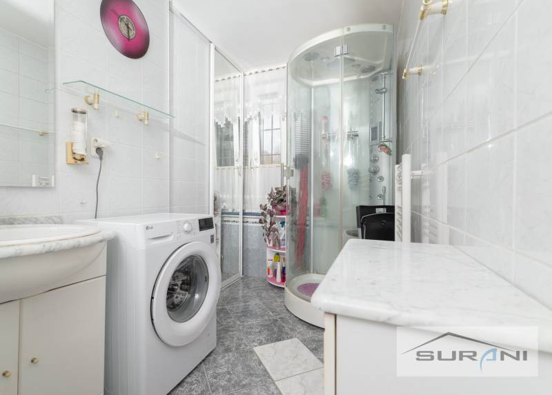 Bathroom in a 3-room apartment with a washing machine, shower corner, and wall decoration.