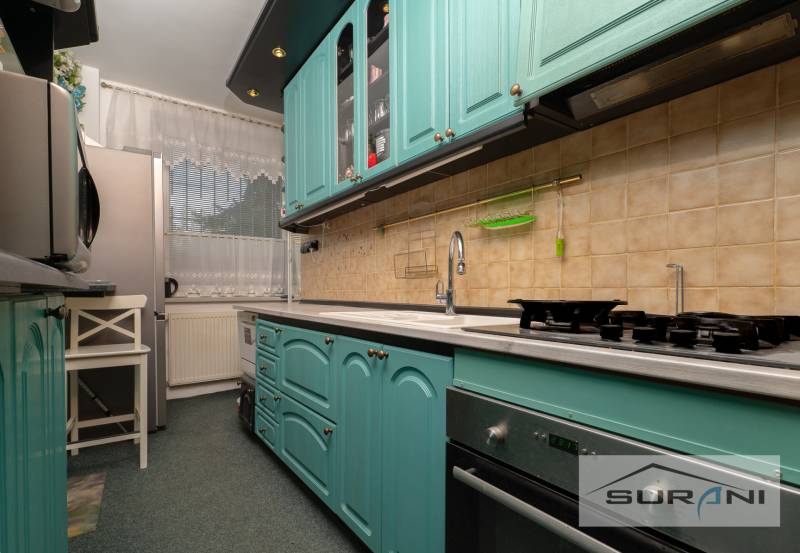 A kitchen with green cabinets, an oven, and a window in a 3-room apartment.