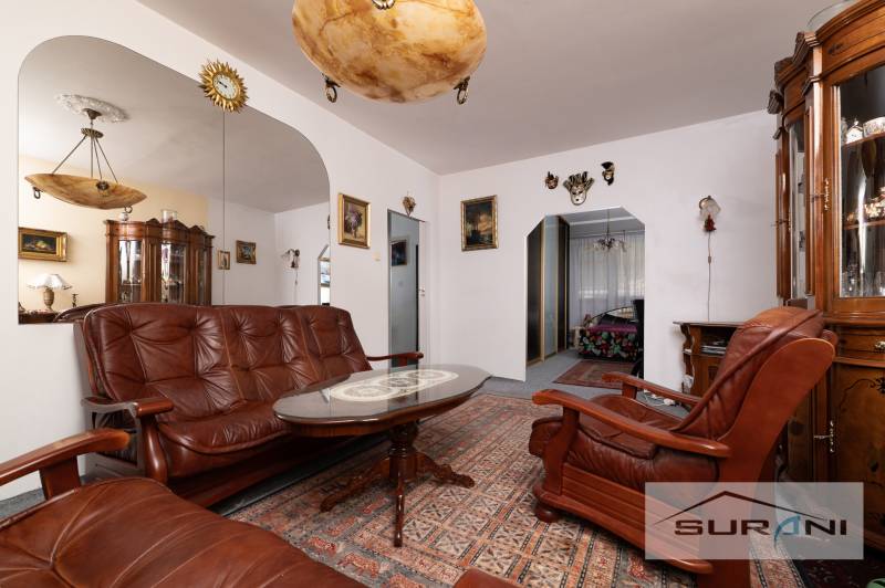 Living room in a three-room apartment with a sofa, armchairs, and a decorative mirror on the wall.