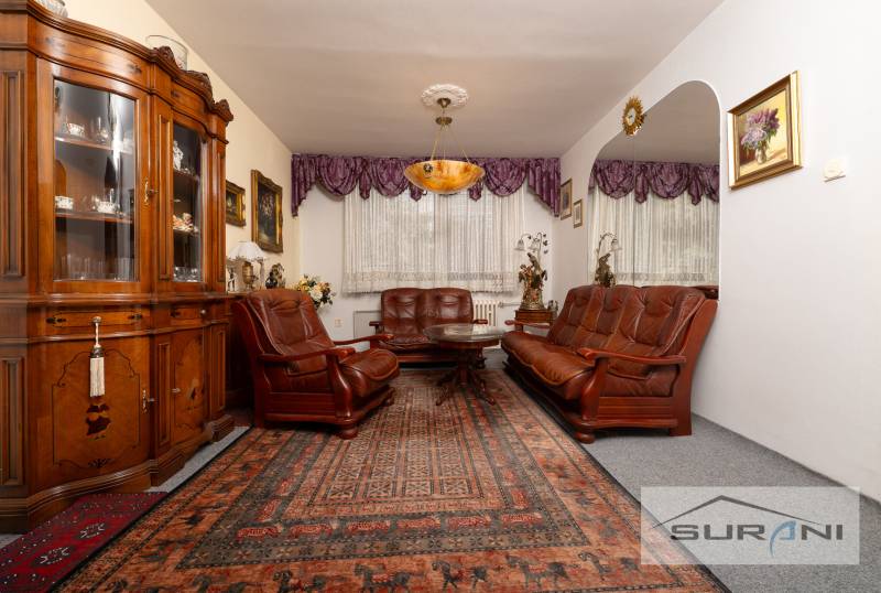 A classic living room in a three-room apartment with wooden furniture and a carpet.