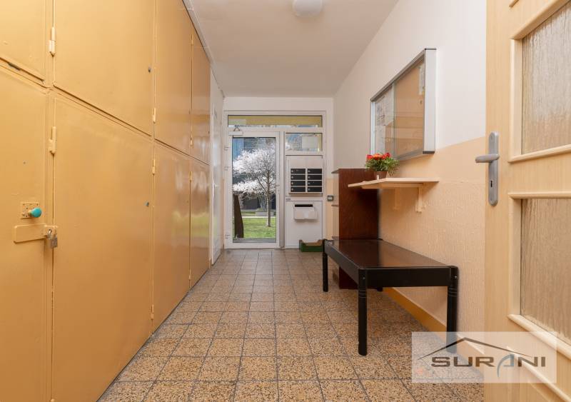 A hallway with storage spaces and a bench, view of blooming trees.