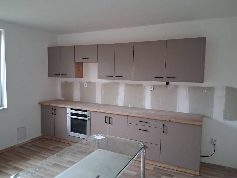 A kitchen in a family house with a wooden decor floor and gray cabinets.