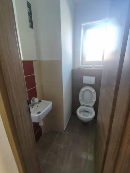 Bathroom in a family house with a sink and toilet, tiled floor.
