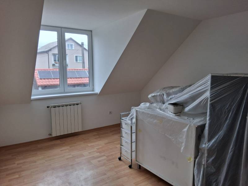 A room in a family house with a window, a heating element, and a floor with a wooden decor.