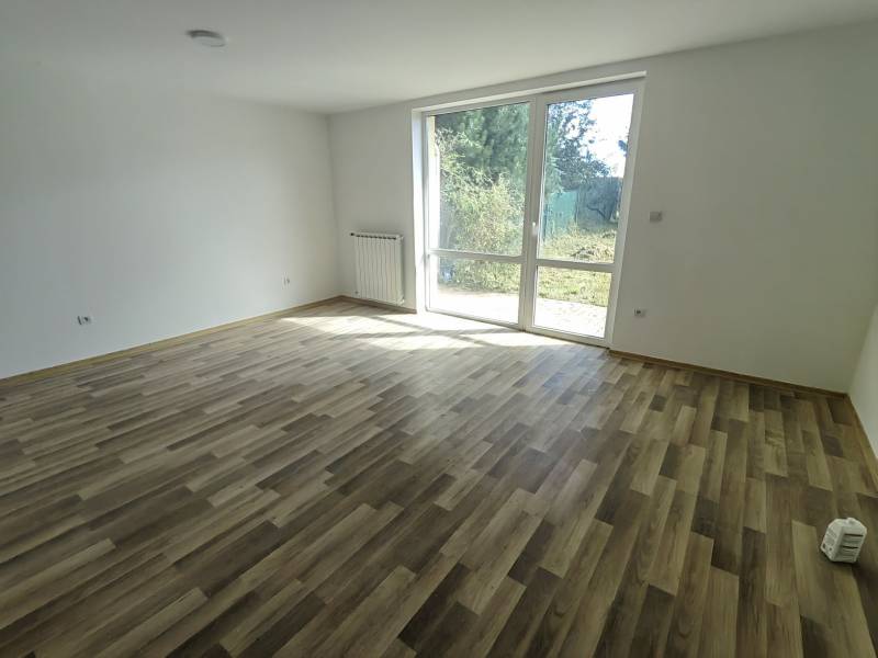 A spacious room with a wooden decor floor and a large window in a family house.