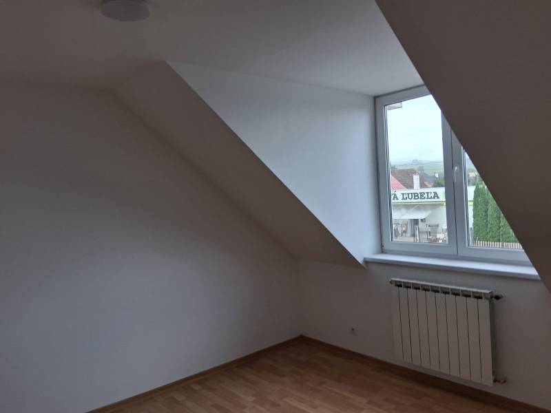 An attic room with a window and a wooden decor floor in a family house.