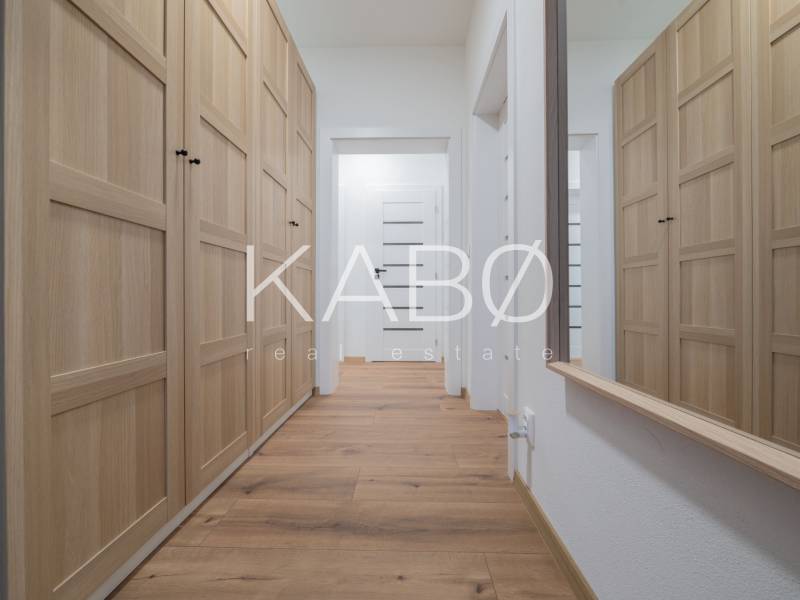 A hallway in a family house with plenty of storage space and a wooden-patterned floor.