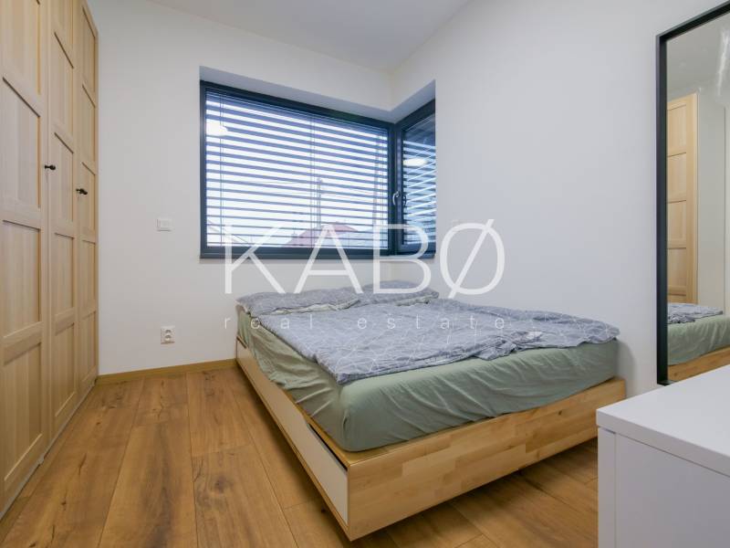 A bedroom in a family house with a bed, wardrobes, and a floor with a wooden decor.