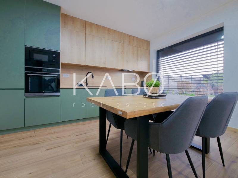 A kitchen in a family house with a wood-patterned floor, green cabinets, and a dining table.