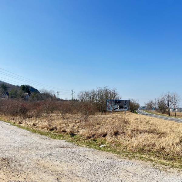 Commercial land in Bratislava - Devínska Nová Ves, next to the road, bordered by shrubs.