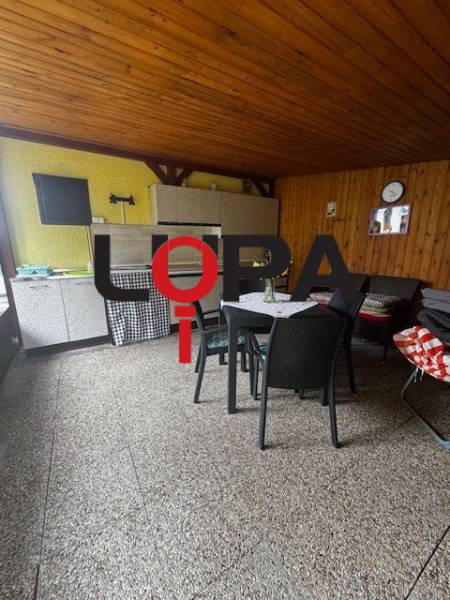 Covered terrace in a cabin with wooden decor, comfortable furniture, and a table for relaxation.