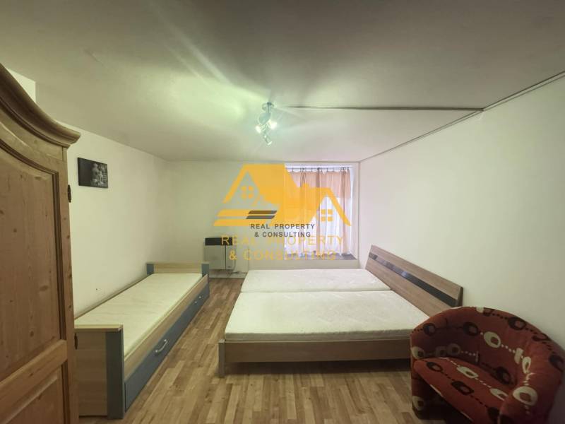 Bedroom in a 2-room apartment with a bed, wardrobe, and floor with wooden decor.