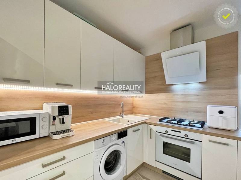 A kitchen in a 2-room apartment with modern appliances and a wooden decor floor.