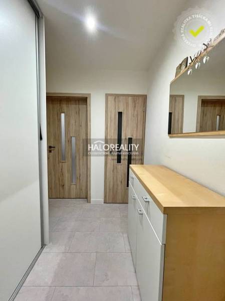 Hallway of a 2-room apartment with sliding doors, wood-patterned flooring, and a mirror.