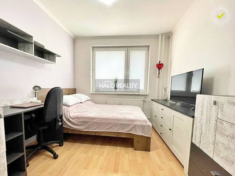 Bedroom in a two-room apartment with a bed, desk, and television. Floor with wooden decor.