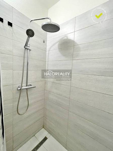 A shower corner with white tiles in a 2-room apartment.
