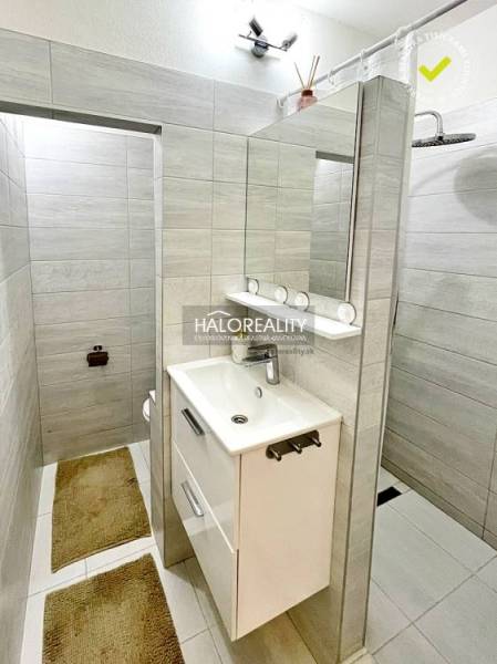 A bathroom with a white sink and a large mirror in a 2-room apartment.