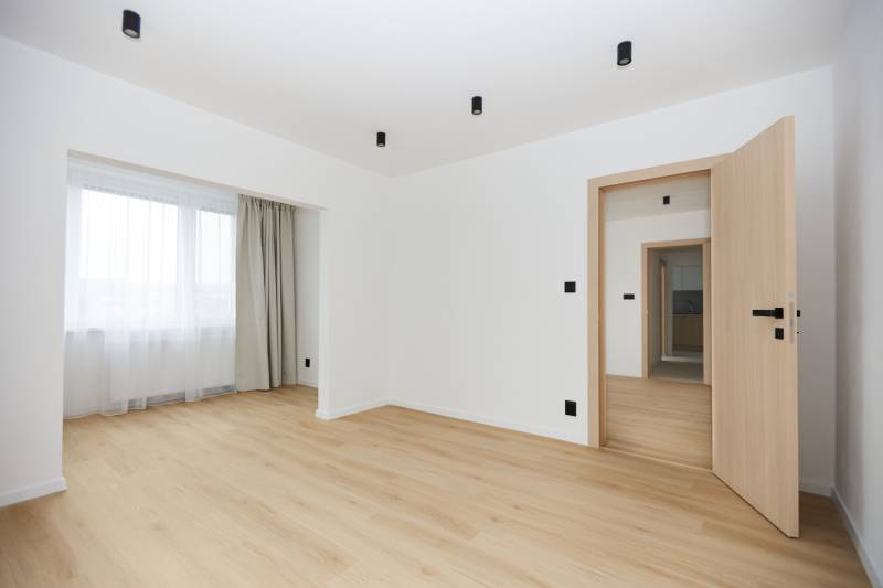 A room with a wooden floor decor and curtains in a 3-room apartment.