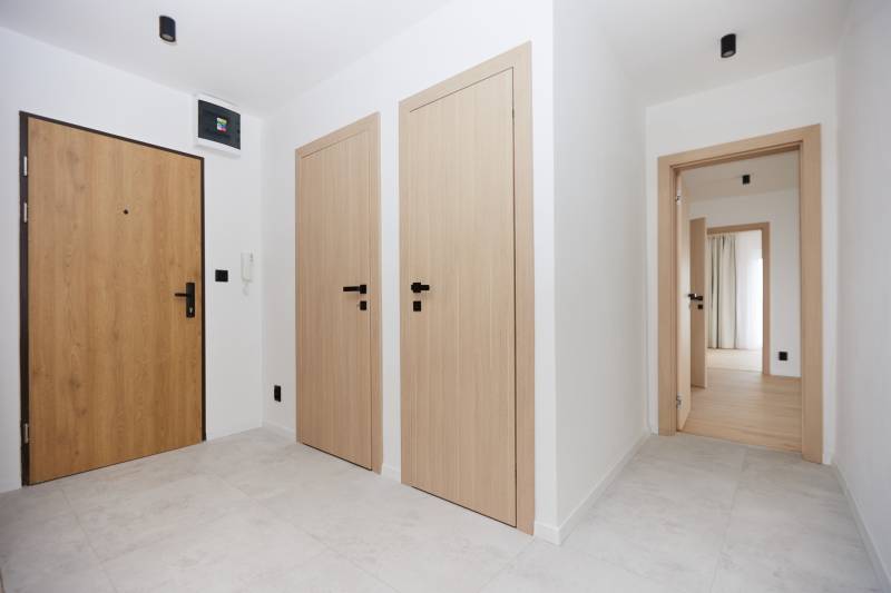 A bright hallway with wooden doors and a curtain in a 3-room apartment.