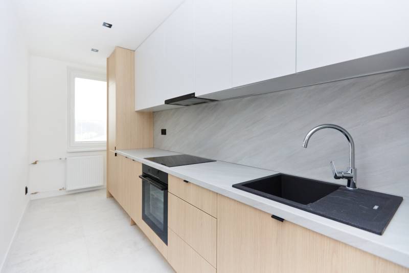 A kitchen in a 3-room apartment with a simple set-up and a black sink.